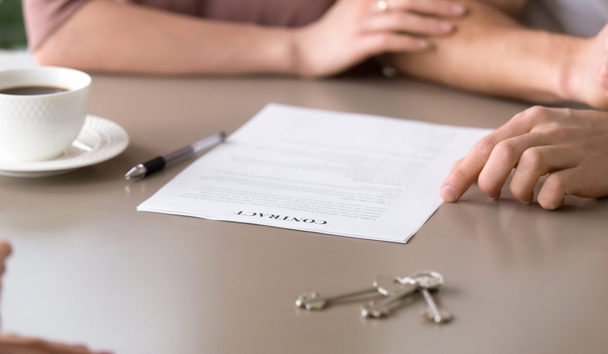 Close up photo of mortgage contract and keys on the table. Couple decided to take out mortgage for buying own apartment, family found reliable building company and purchasing new house