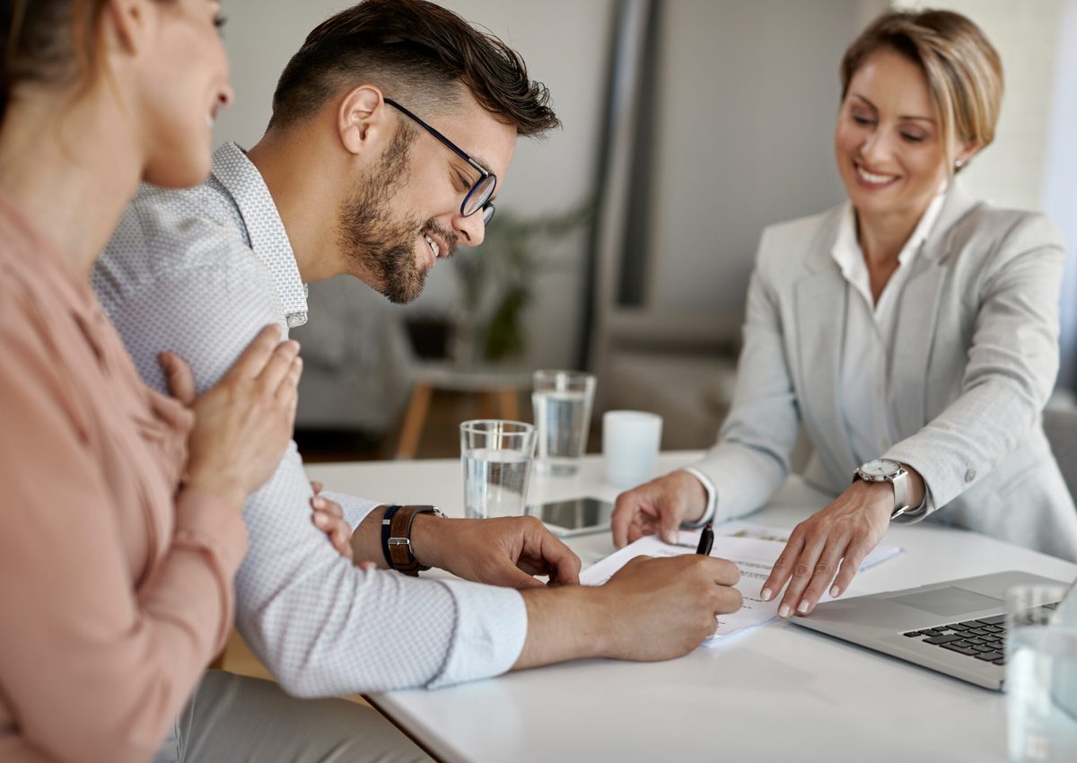 Happy man and his wife having a meeting with financial advisor and signing an agreement in the office.